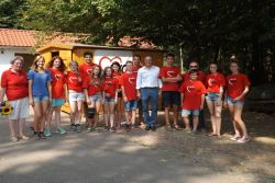 Gruppenfoto von Jugendlichen und Erwachsenen in AWO-Shirts vor einer Holzhütte.