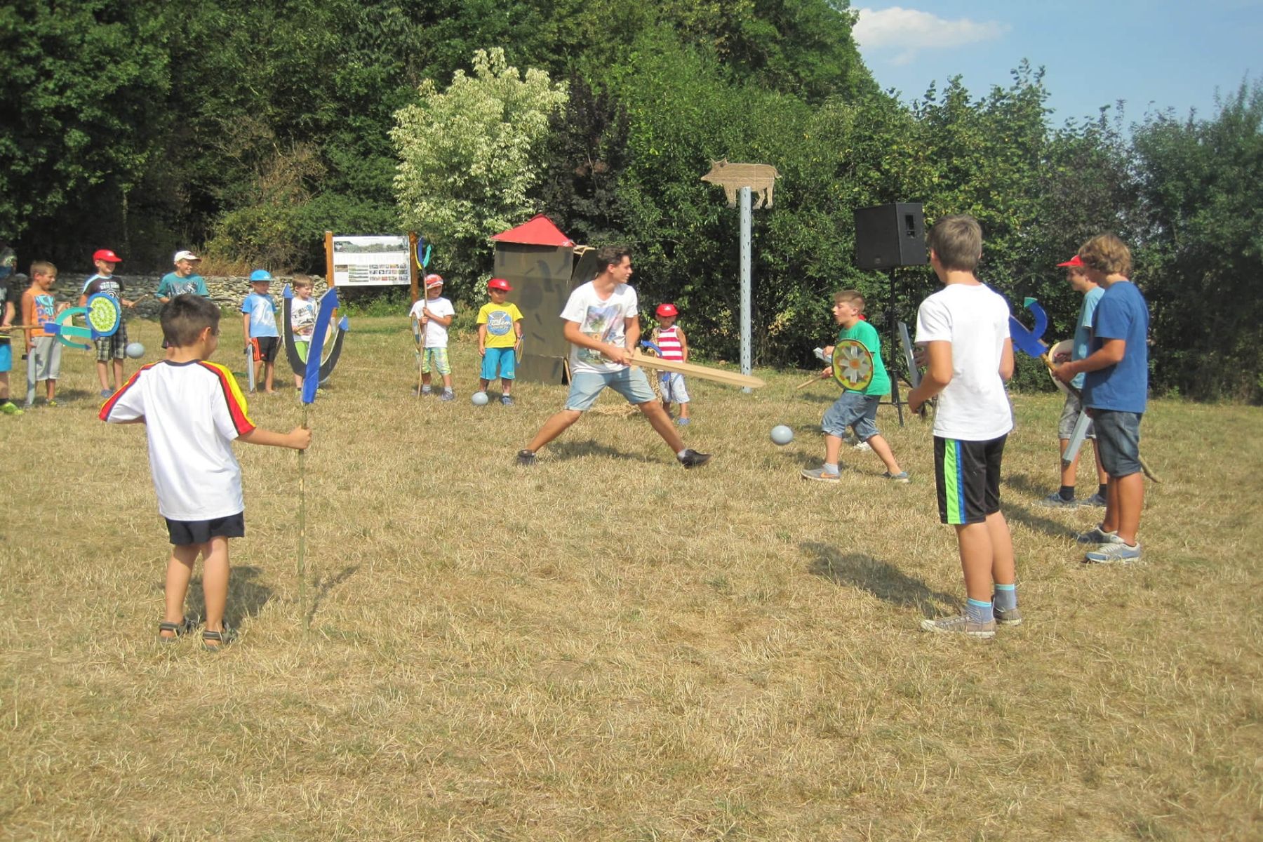 Kinder spielen draußen mit selbstgebastelten Schwertern und Schilden.