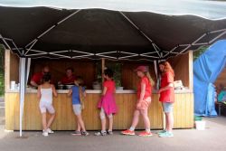 Kinder und Jugendliche stehen an einem Essensstand unter einem Pavillon.